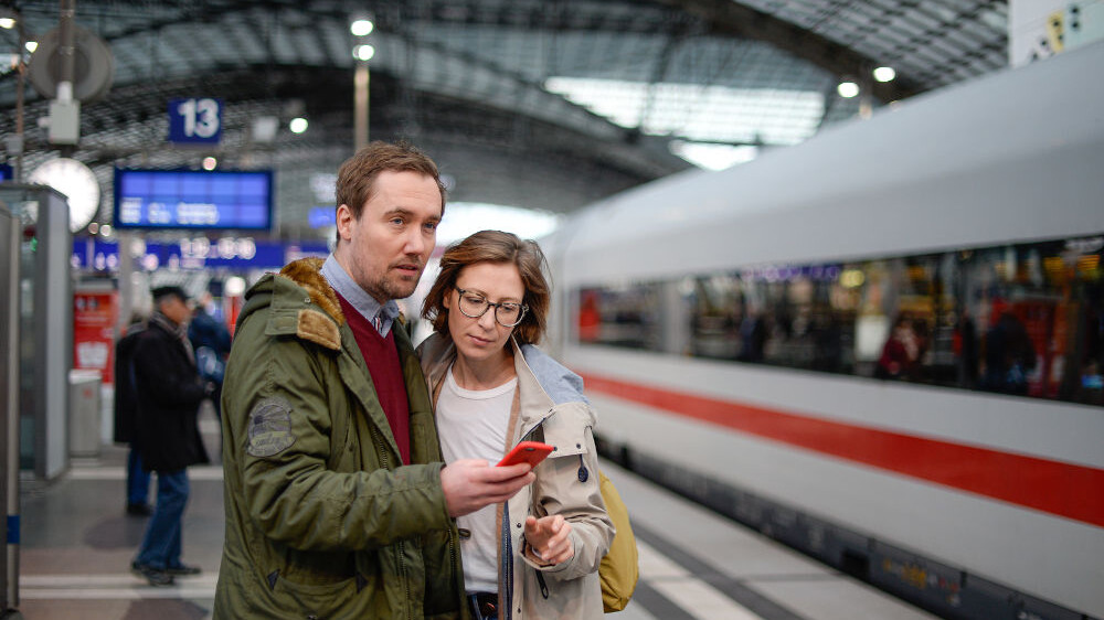 Digitale BahnCard - Reisende mit Smartphone am Bahnhof